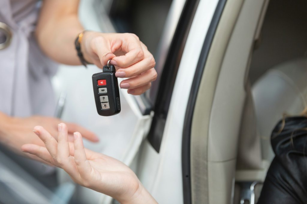 Customer hand receiving car key from agent dealer
