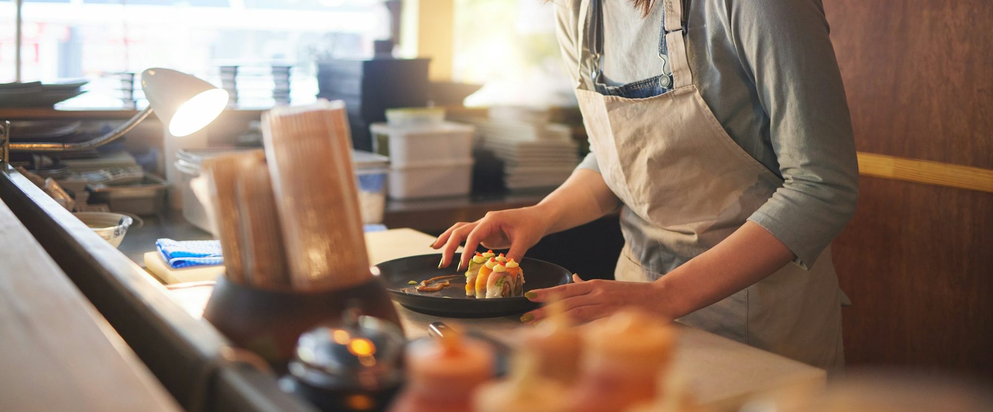 Sushi, restaurant worker and woman with smile from food and Asian meal in a kitchen. Happy, female